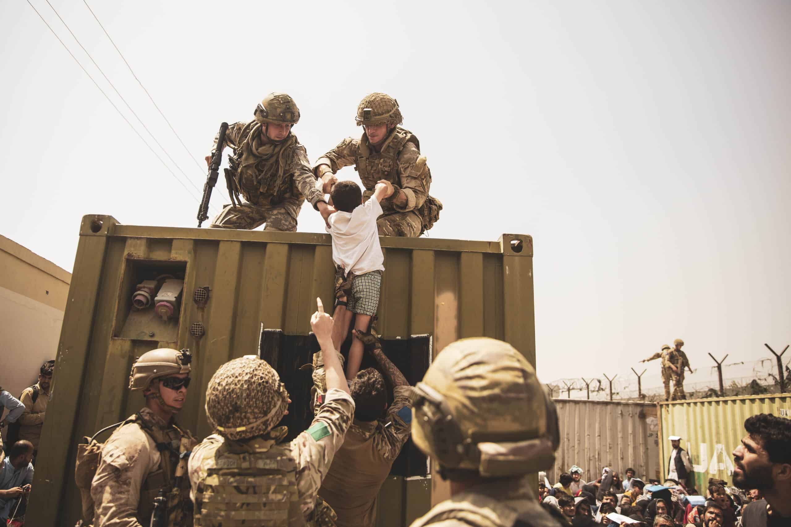 UK coalition forces, Turkish coalition forces, and U.S. Marines assist a child while evacuating Afghanistan