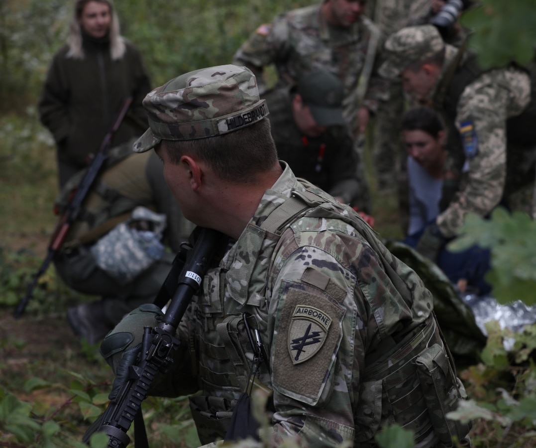 U.S. Army Sgt. Clayton Hildebrandt, a civil affairs noncommissioned officer with the Civil Military Operations Center, looks over his shoulder as Ukraine soldiers administer first aid to a simulated casualty