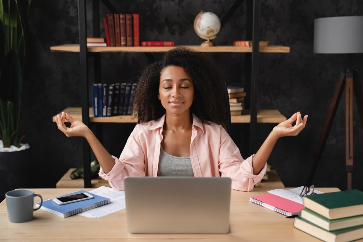 Young african freelancer worker businesswoman student meditating at workplace desk