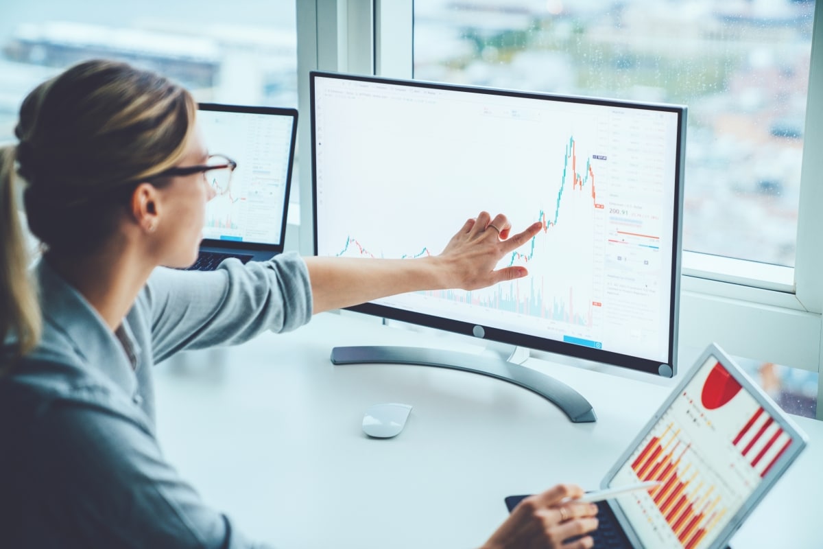 Business woman study financial market to calculate possible risks and profits.Female economist accounting money with statistics graphs pointing on screen
