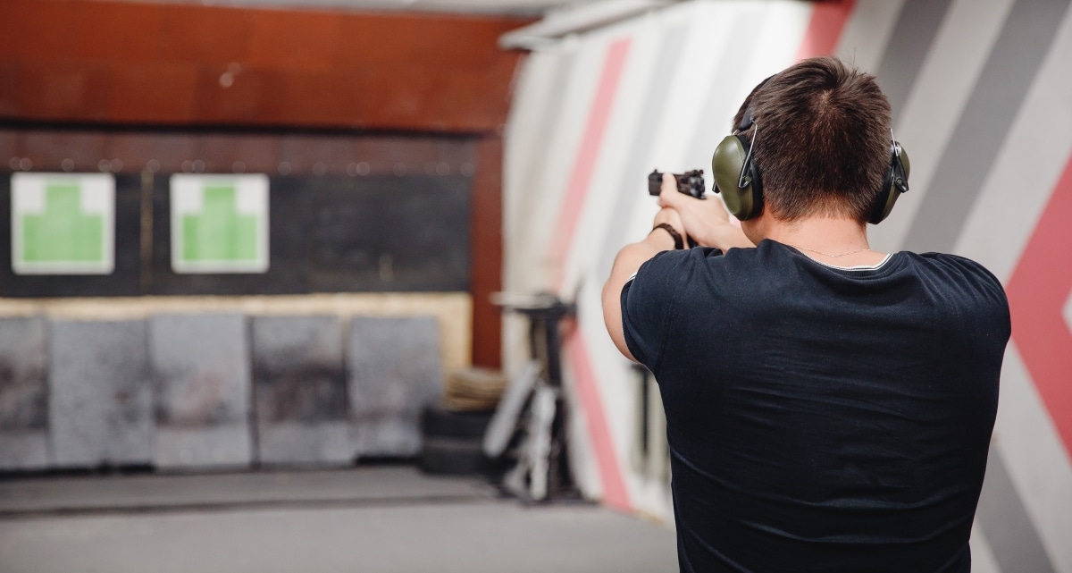 Man directs firearm gun pistol at target firing range or shooting range.