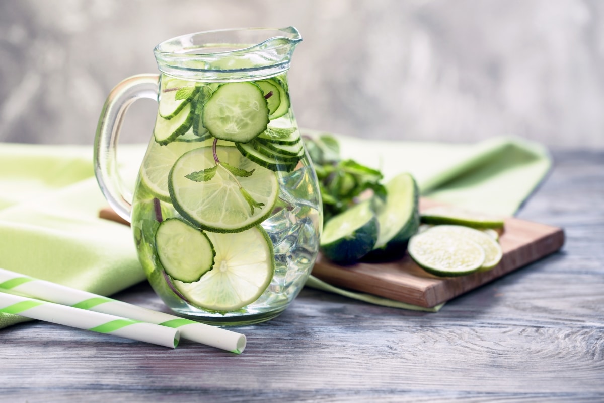 Infused water with cucumber, lime and mint on grey rustic background