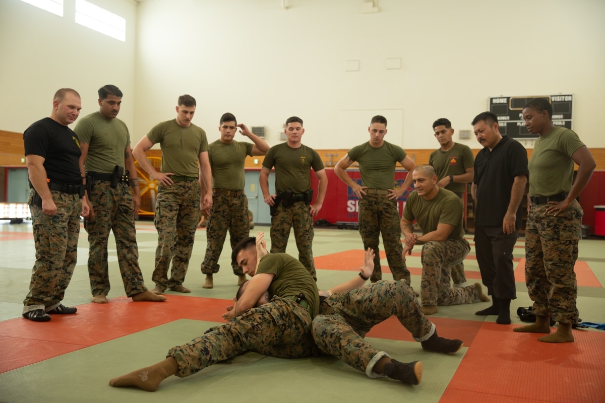 U.S. Marines and civilian law enforcement personnel observe a technique during a demonstration at Camp Hansen, Okinawa, Japan