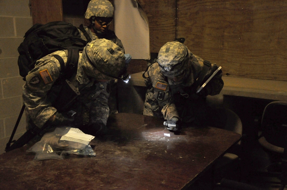 Three members of the multi-function team, part of the 636th Military Intelligence Battalion, collect fingerprints in an effort to identify who carried out the murders of the villagers in the notional scenarios during a two-week exercise at Joint Base San Antonio-Camp Bullis