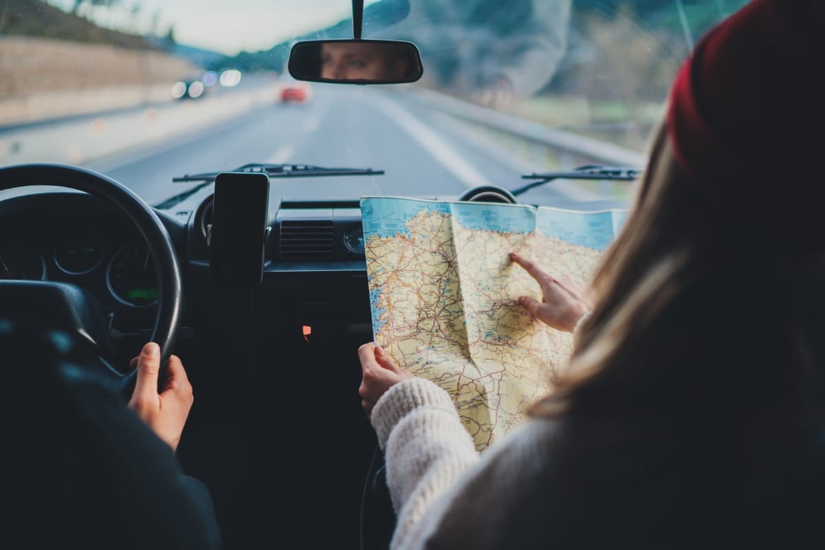 Happy couple traveling by authentic car in Europe, hipster girl holding touristic map planning route in mountains, lifestyle roadtrip travel concept