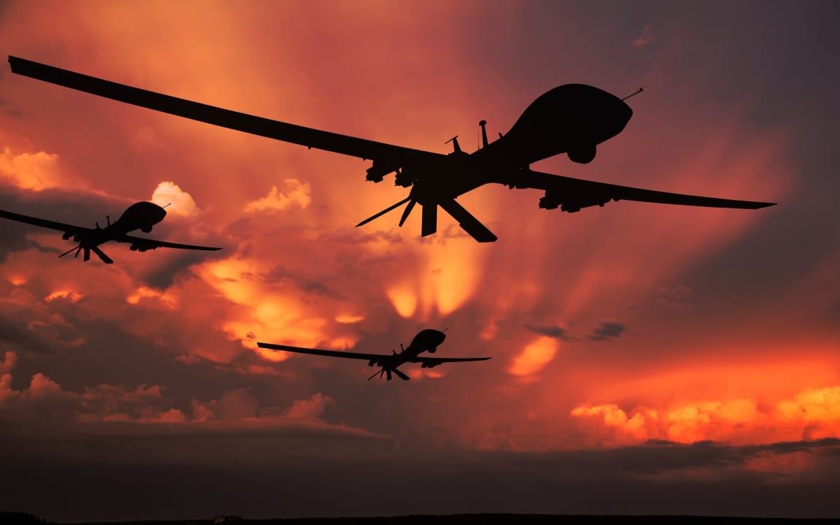 Three military drones silhouettes. Armed with missiles. Yellow sky background. 3D illustration.