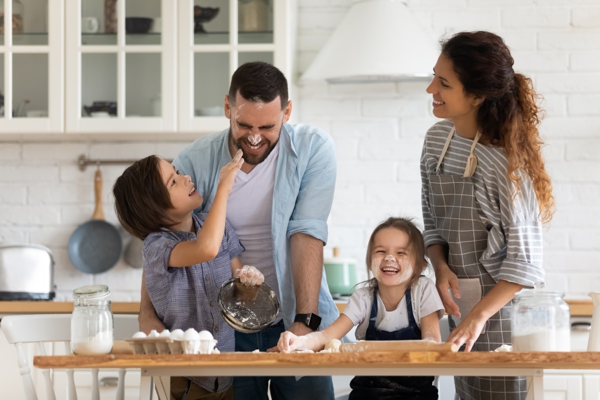 Overjoyed young family with little preschooler kids have fun cooking baking pastry or pie at home together