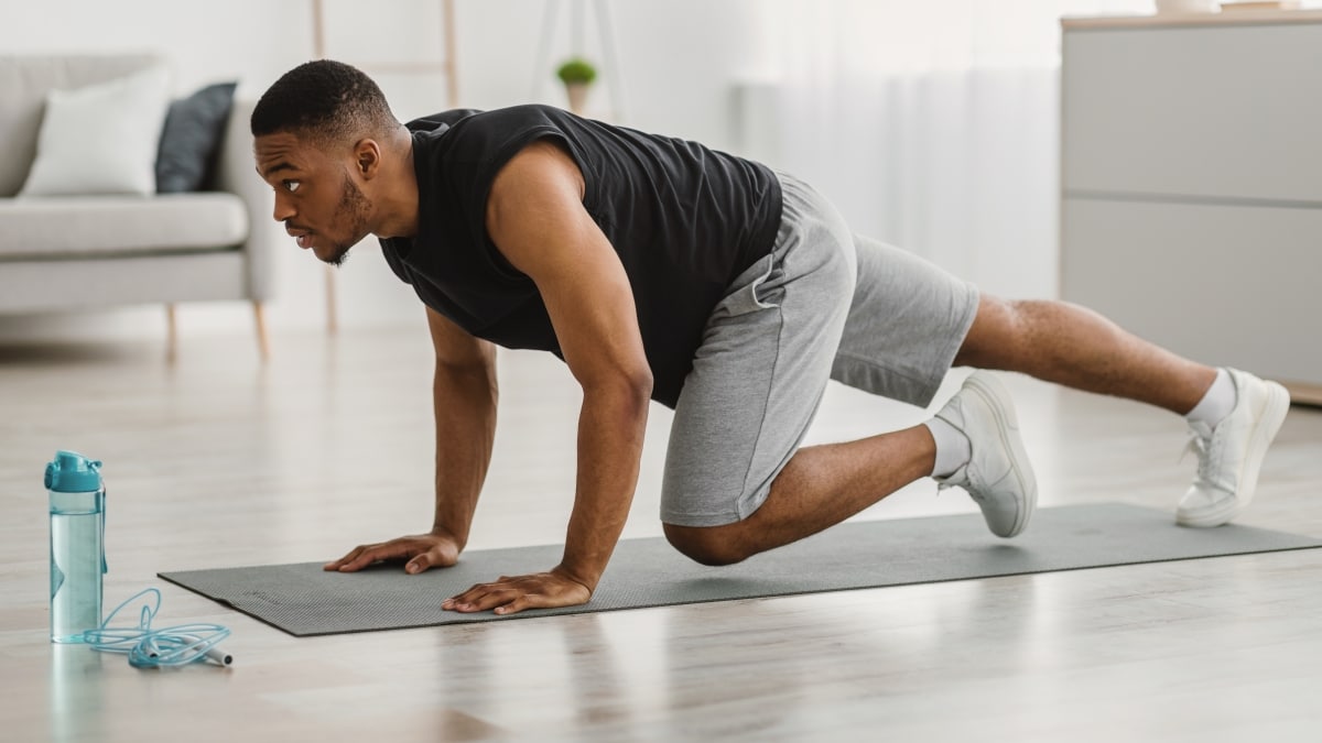Sporty African American Man Doing Running Plank Exercise At Home. Side View Of Athletic Guy Training In Living Room. Male Fitness Workout And Bodybuilding. Sport Motivation Concept. Panorama