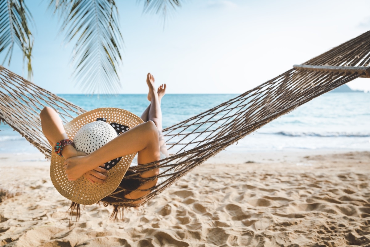Summer travel vacation concept, Happy traveler asian woman with white bikini relax in hammock on beach in Koh mak, Thailand