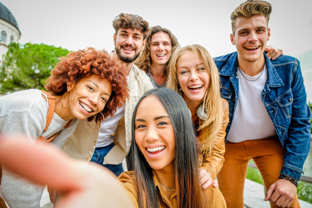 Multiracial happy friends having fun and laughing together outdoors taking selfie portrait on city street - Happy lifestyle and friendship concept