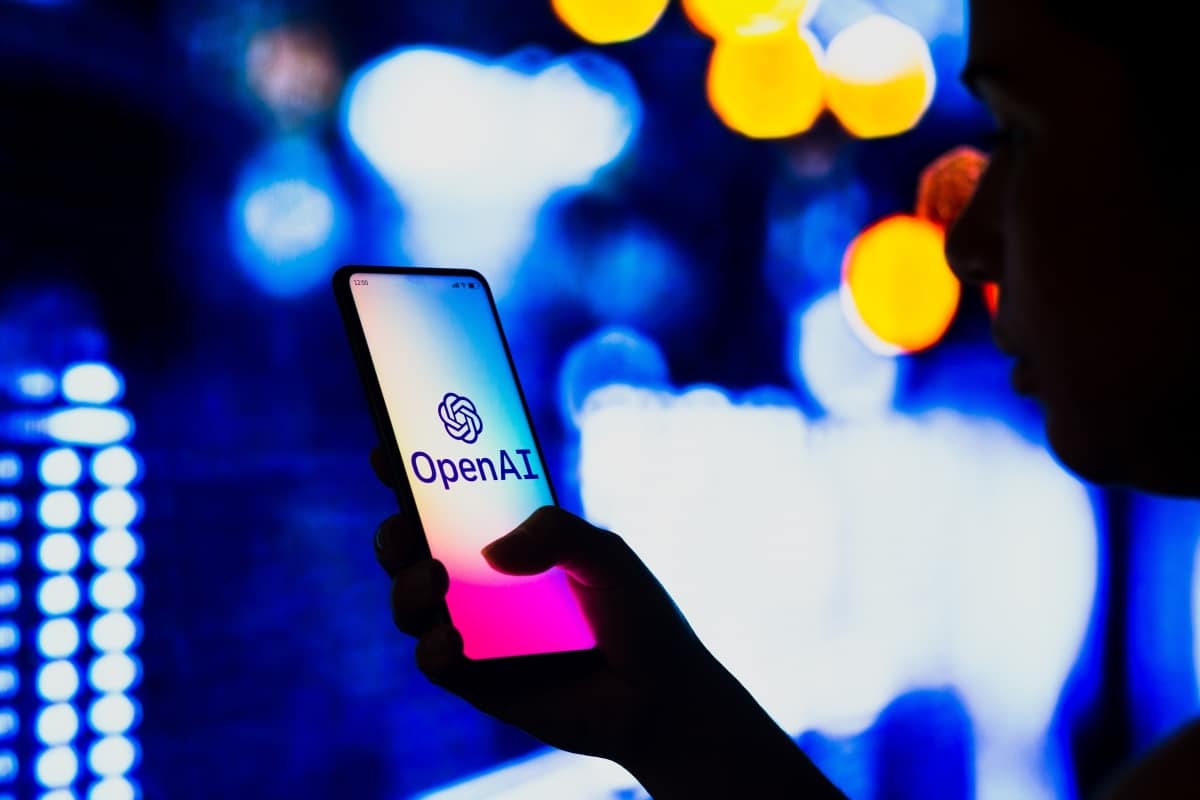 October 2, 2022, Brazil. In this photo illustration, a silhouetted woman holds a smartphone with the OpenAI logo displayed on the screen