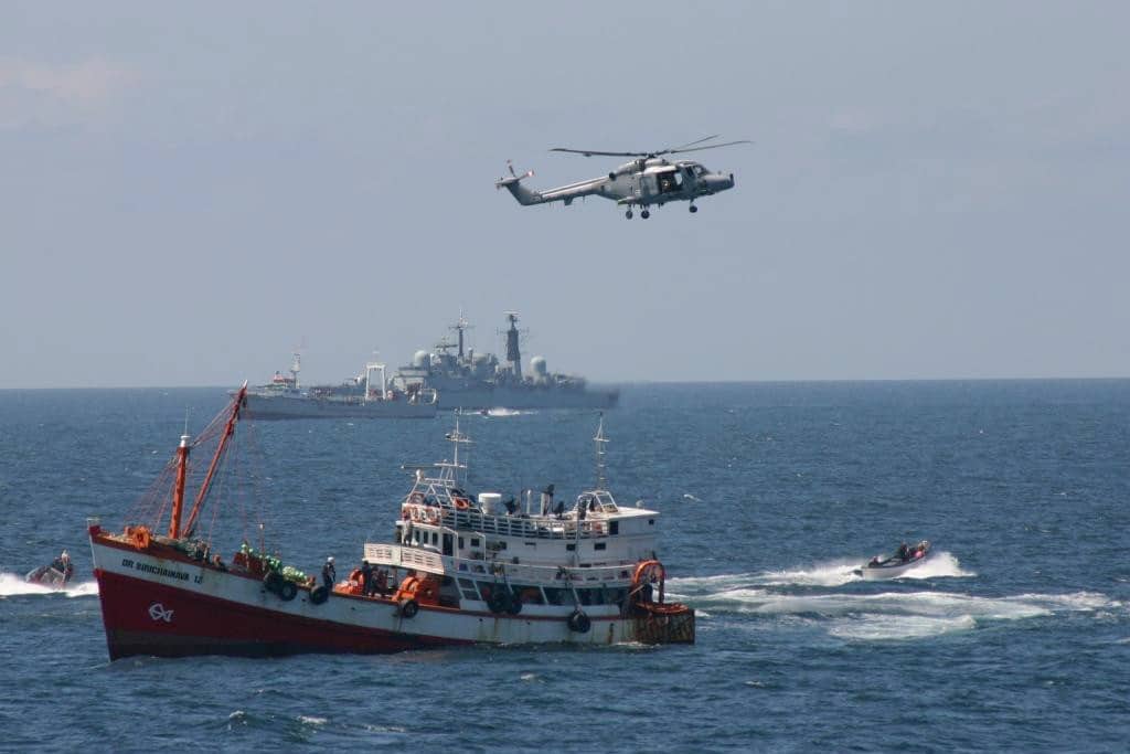 GULF OF ADEN, NORTH AFRICA (Mar. 17, 2005)--A British helicopter from the HMS Invincible and two small boats from the Coast Guard Cutter Munro provide cover as a Coast Guard boarding team takes control of the hijacked Thai fishing vessel and custody of the highjackers along with an assortment of automatic weapons