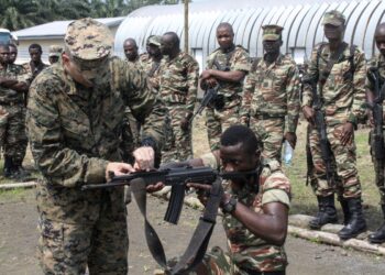 Staff Sgt. Benjamin Lacasse, a platoon sergeant with Special Purpose Marine Air-Ground Task Force Crisis Response-Africa, adjusts sights for a soldier with the Cameroonian Naval Commando Company in Limbé