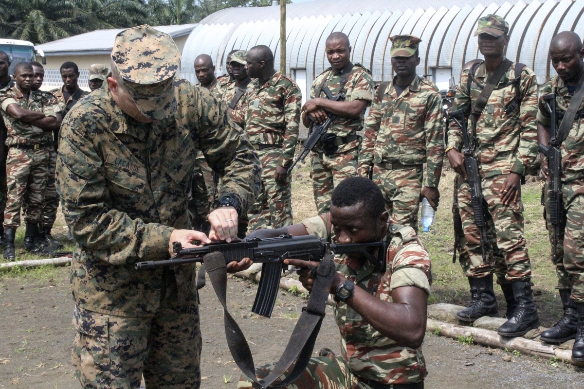 Staff Sgt. Benjamin Lacasse, a platoon sergeant with Special Purpose Marine Air-Ground Task Force Crisis Response-Africa, adjusts sights for a soldier with the Cameroonian Naval Commando Company in Limbé