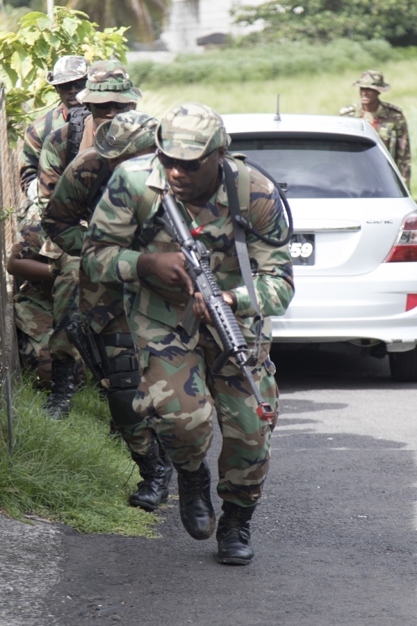Members of the Royal Grenada Police Force move to secure perimeter of Saint Vincent and the Grenadines police station during a simulated breach exercise for phase II of tradewinds