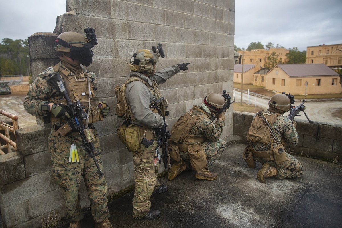 U.S. Marines with 2d Battalion, 6th Marine Regiment, 2d Marine Division and a U.S. Army Green Beret with 3rd Special Forces Group, hold security on a rooftop during a Military Operations in Urban Terrain