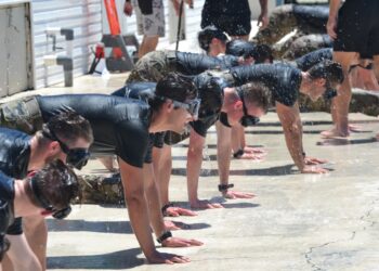 Candidates wait for instruction in the front leaning rest position at the Flooded Mask Flutter-Kick Beatdown station during Hell Day at Bobby Hicks Pool in Tampa