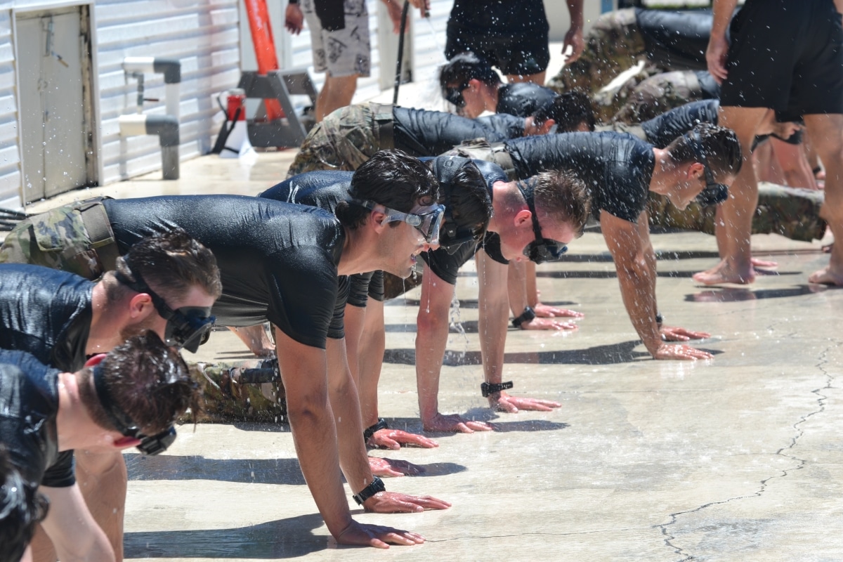 Candidates wait for instruction in the front leaning rest position at the Flooded Mask Flutter-Kick Beatdown station during Hell Day at Bobby Hicks Pool in Tampa