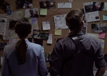 Secret agency teammates searching for criminal movements on investigation board