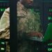 Close up of young African American military officer checking work of servers in analytic monioring center. Man with laptop computer control networking in dark room Cybersecurity in army concept.