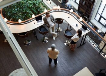Top-view of handsome young man and beautiful young woman talking to a senior woman in a coworking space