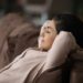 Calm young Indian woman relax on couch at home sleep or take nap relieving negative emotions.