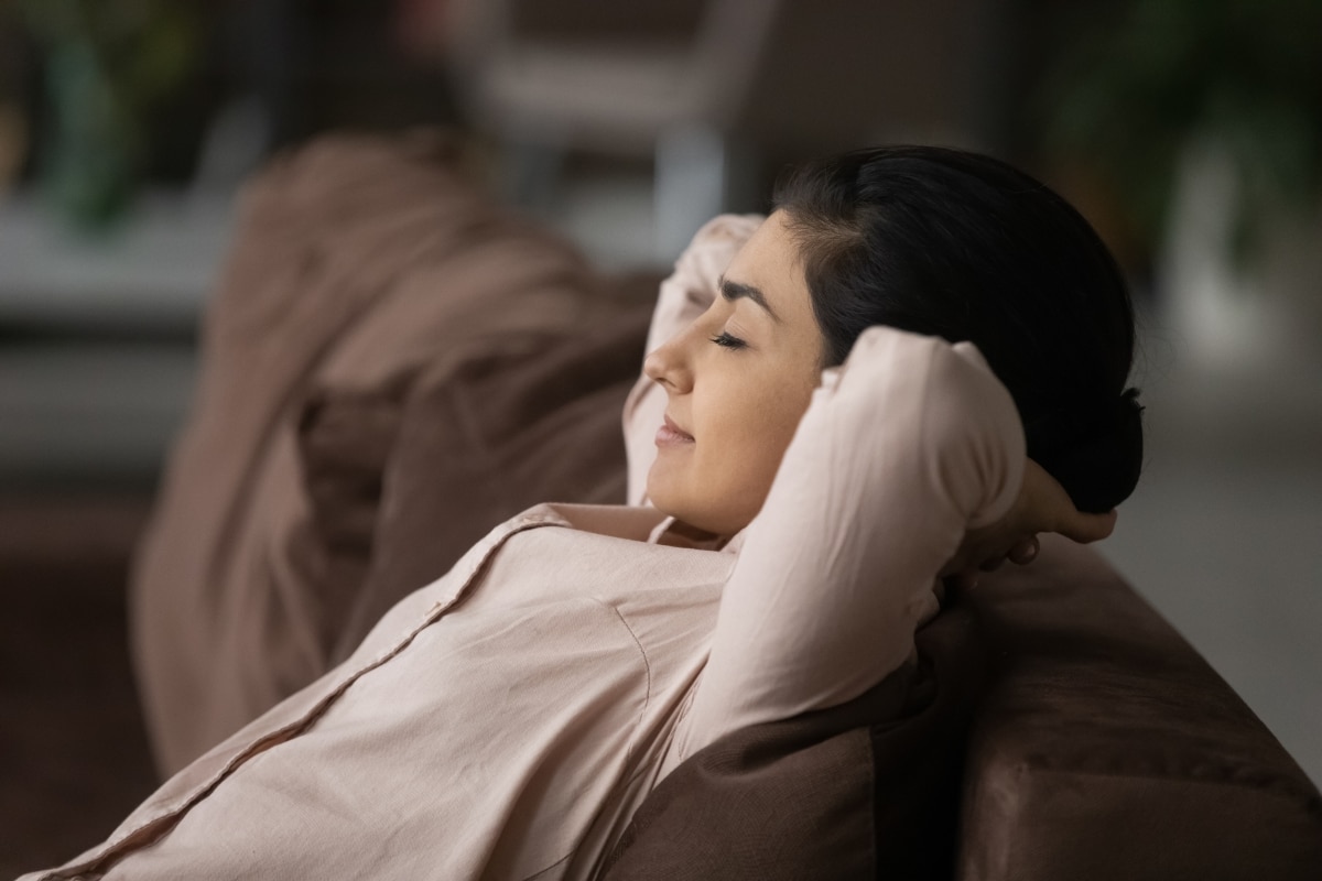 Calm young Indian woman relax on couch at home sleep or take nap relieving negative emotions.