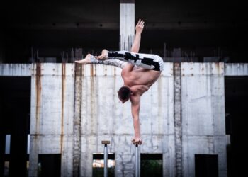 Flexible male circus Artist keep balance by one hand in the concrete structure. Confidence and aspiration concept.