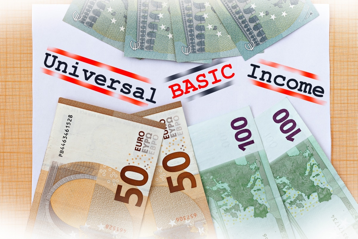 Universal Basic Income theme. The words Basic Income on paper, surrounded by dollar and euro bills