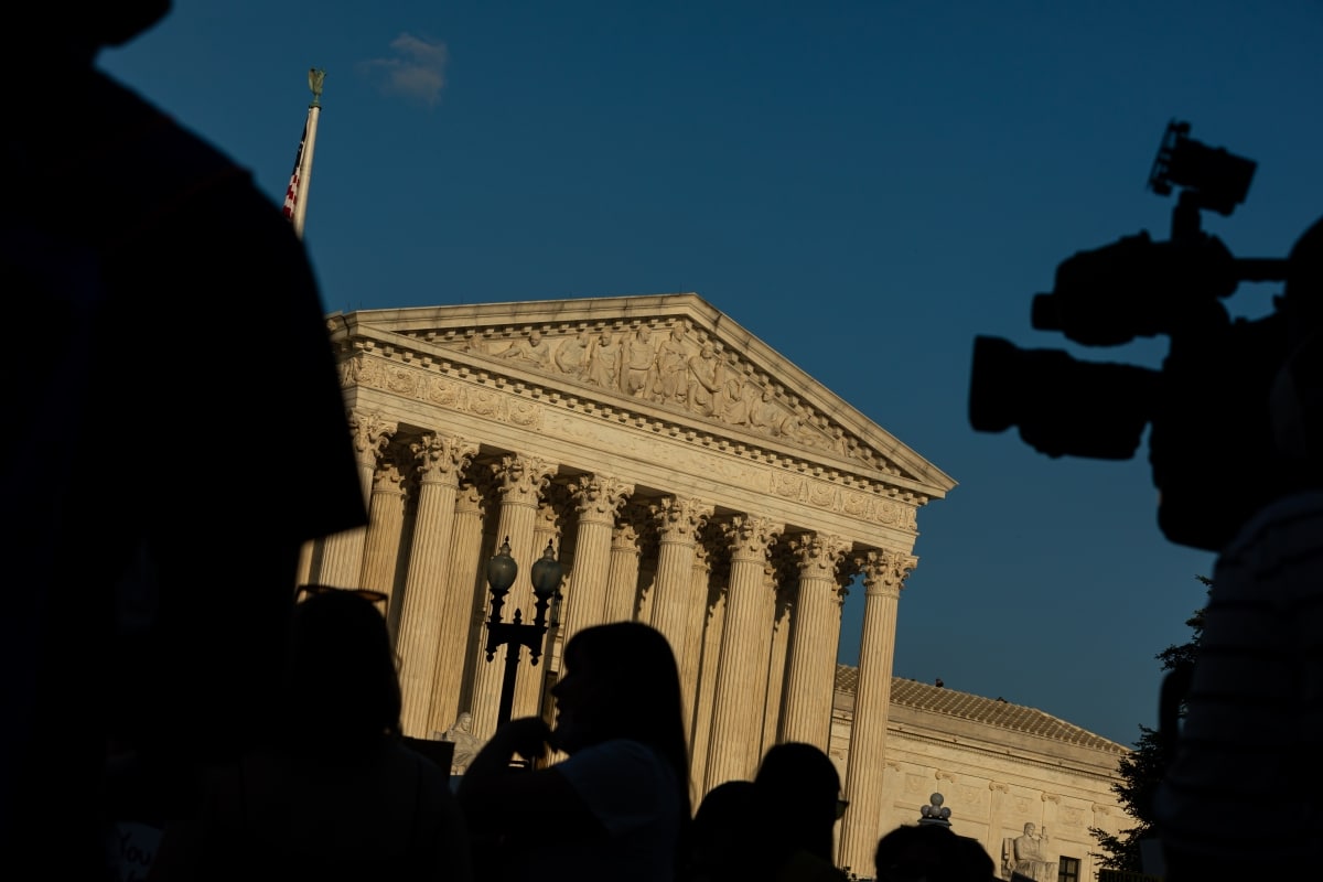 US Supreme Court Building in Washington, DC with Protestors' and TV Camera's black Silhouettes in Foreground during a Protest