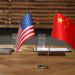 USA and China flags on wooden table in office. International relations