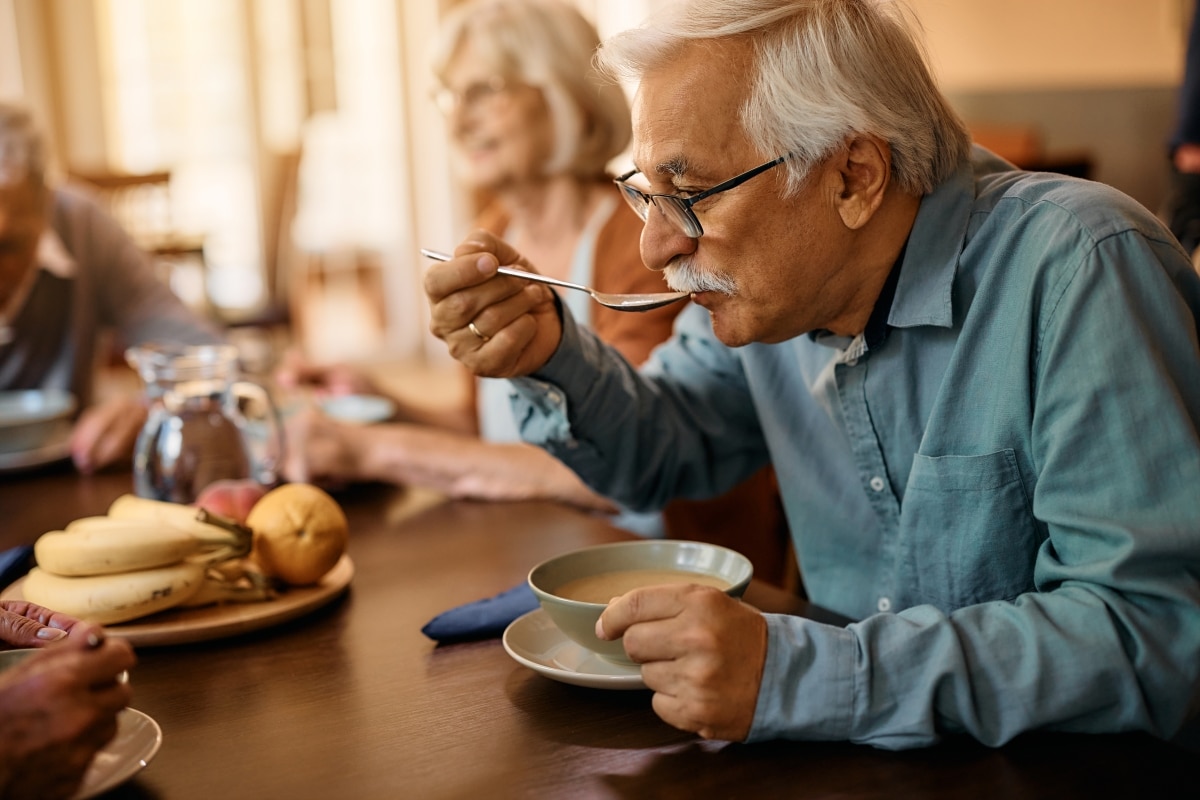 Mature man eating soup while having lunch at residential care home