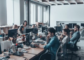 Busy working day. Group of young business people concentrating at their work while sitting at the large office desk in the office together