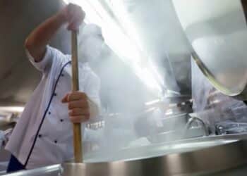 Abstract, blurry, bokeh background, image for the background. A cook on a ship preparing food in a large cauldron