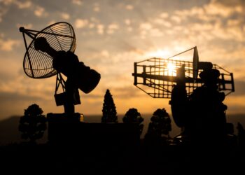 Silhouettes of satellite dishes or radio antennas against night sky. Space observatory or Air defence radar over dramatic sunset sky. Creative artwork decoration. Selective focus