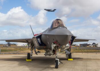 Adelaide, South Australia / Australia - Nov 08 2019: ADF RAAF F-35 Joint Strike Fighter (JSF) sits on the runway display for RAAF Edinburgh Airshow 2019 as a cargo plane departs in the background.