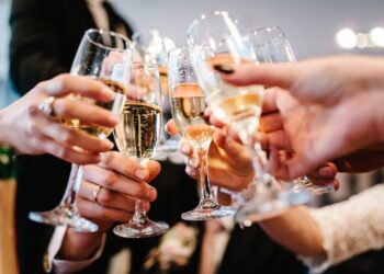 Cheers! People celebrate and raise glasses of wine for toast. Group of man and woman cheering with champagne.