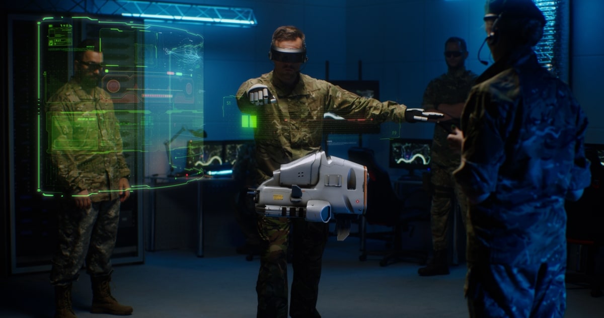Man in camouflage uniform and goggles using controllers to operate modern military UAV