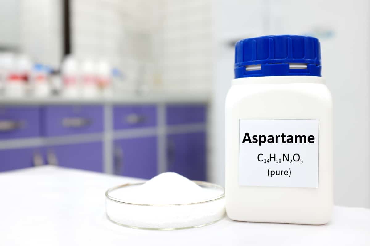 Selective focus of a bottle of pure aspartame artificial sweetener sugar substitute. White laboratory background with copy space.