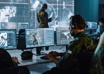 Military Surveillance Officer Working on a City Tracking Operation in a Central Office Hub for Cyber Control and Monitoring for Managing National Security, Technology and Army Communications.