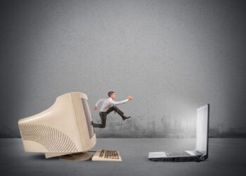 Businessman jumping from old computer to new laptop