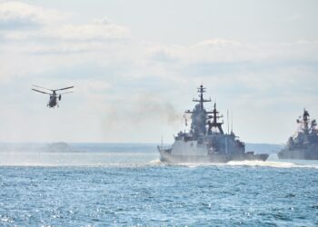 Battleships war ships corvette during naval exercises and helicopter maneuvering over water in Baltic Sea. Warships, helicopters and boats perform tasks in sea, military warships sailing, Russian Navy