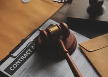 Business and lawyers discussing contract papers with brass scale on desk in office. Law, legal services, advice, justice and law concept picture with film grain effect