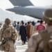 210821-M-GQ845-1042 HAMID KARZAI INTERNATIONAL AIRPORT, Afghanistan (August 21, 2021) Marines with Special Purpose Marine Air-Ground Task Force-Crisis Response-Central Command (SPMAGTF-CR-CC) guide evacuees on to a United Arab Emirates