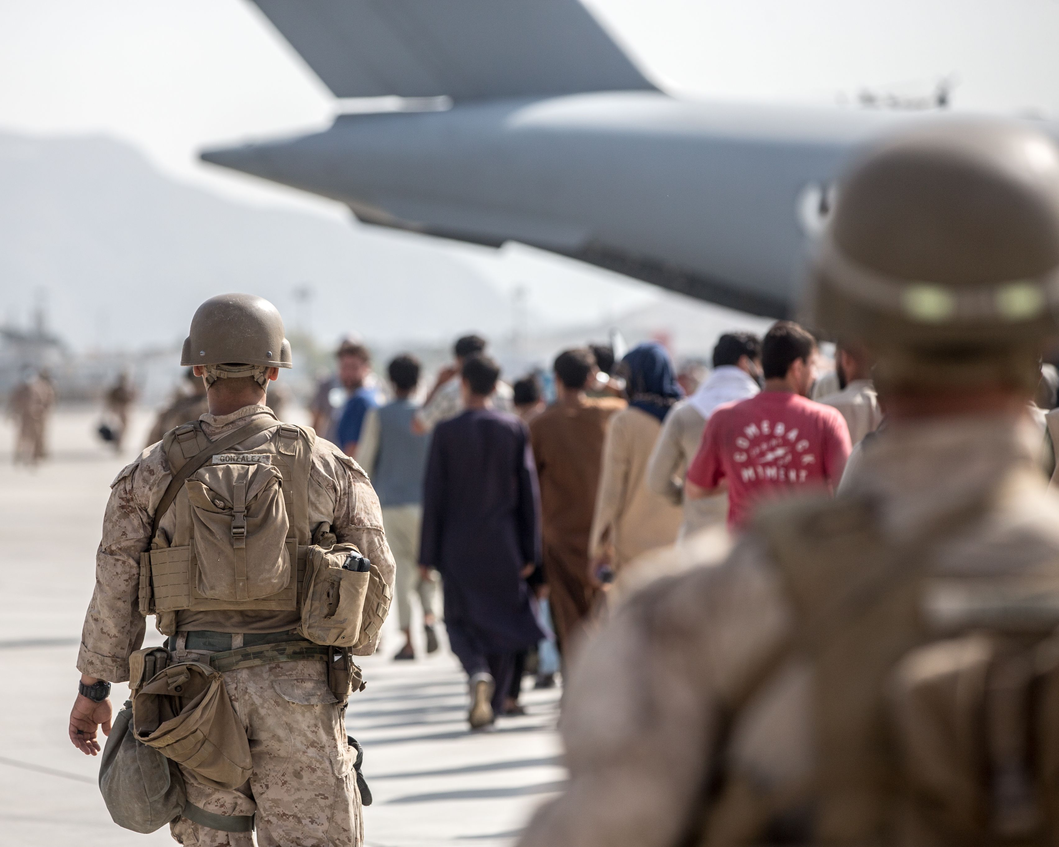 210821-M-GQ845-1042 HAMID KARZAI INTERNATIONAL AIRPORT, Afghanistan (August 21, 2021) Marines with Special Purpose Marine Air-Ground Task Force-Crisis Response-Central Command (SPMAGTF-CR-CC) guide evacuees on to a United Arab Emirates