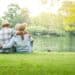 An elderly couple hugging each other with love and happiness in a park with a large pond. Senior community concept, good health, longevity