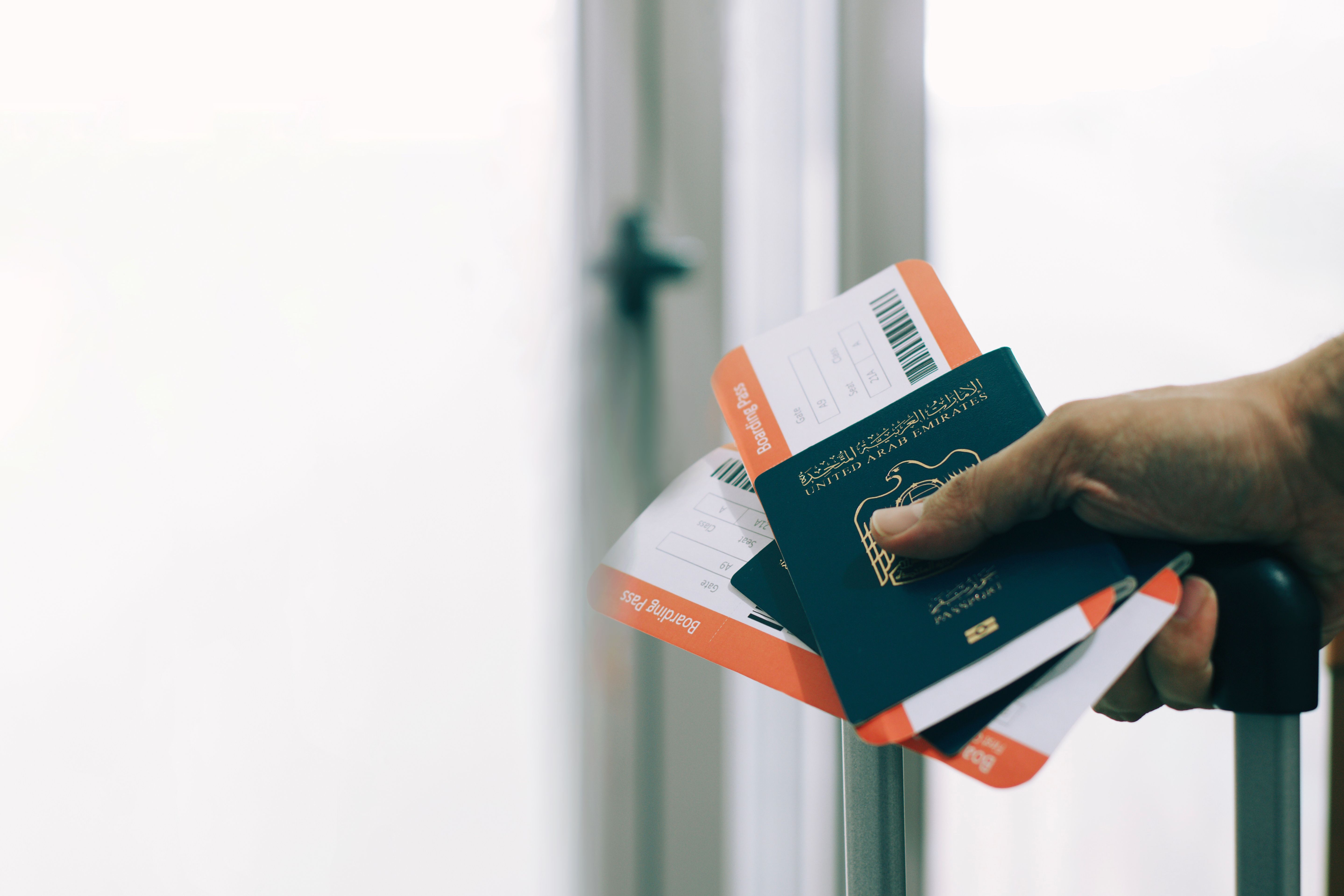 passenger holding uae passports and airline tickets in airport - departures pass gate
