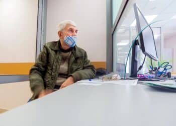 An elderly man writes an application for a pension at the Russian Pension Fund.