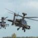 close-up head-on of two British army Boeing Apache Attack helicopters (AH-64E) transition to low level flight, Wiltshire UK