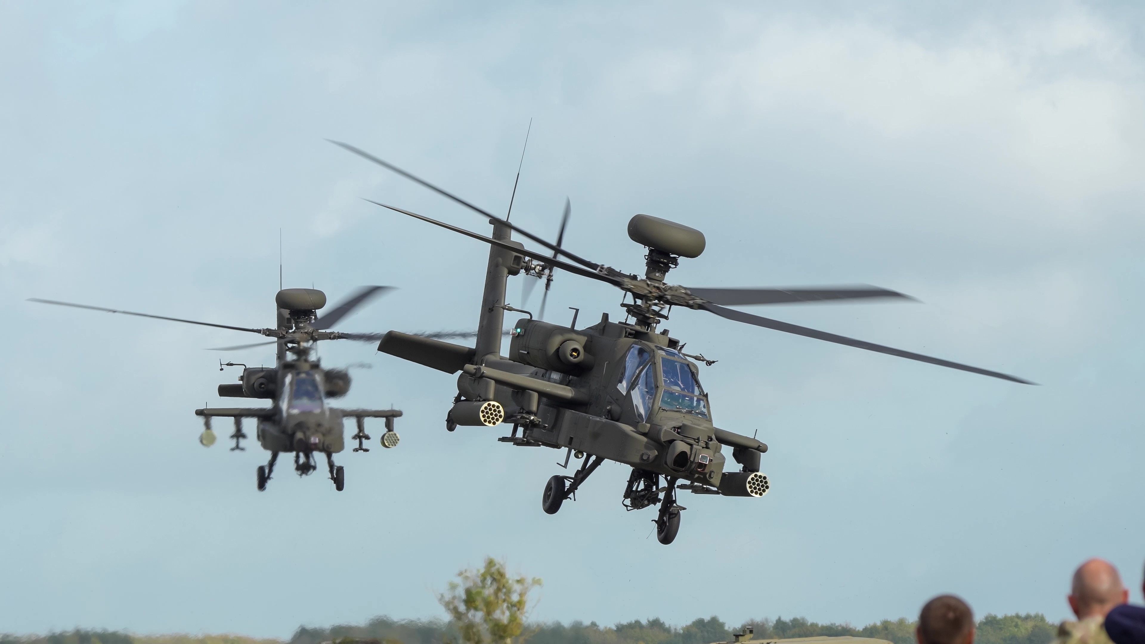 close-up head-on of two British army Boeing Apache Attack helicopters (AH-64E) transition to low level flight, Wiltshire UK